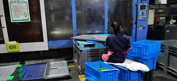 worker performing initial trimming on plastic pallet box worker performing initial trimming on plastic pallet box